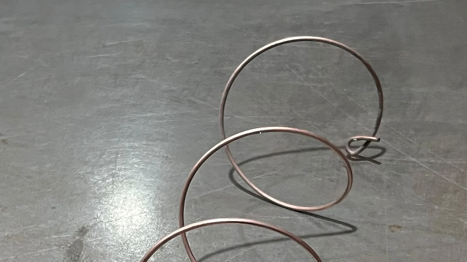 Einzelne Feder aus verkupfertem Draht auf einer Stahlplatte