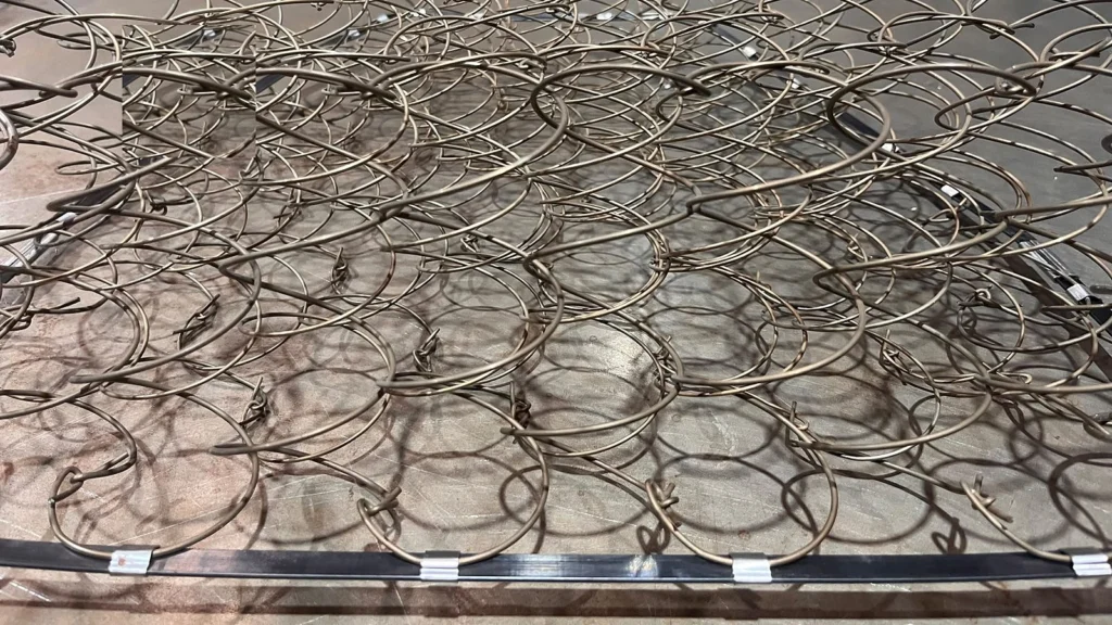 Federn eines Federkerns, mit Metallklammern an der Randeinfassung aus Bandstahl befestigt