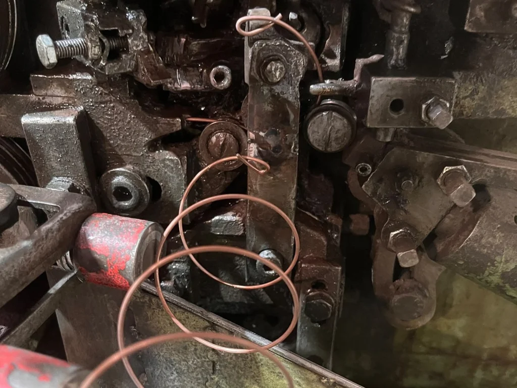 Frisch gewundene Feder aus verkupfertem Draht am Federwindeautomaten