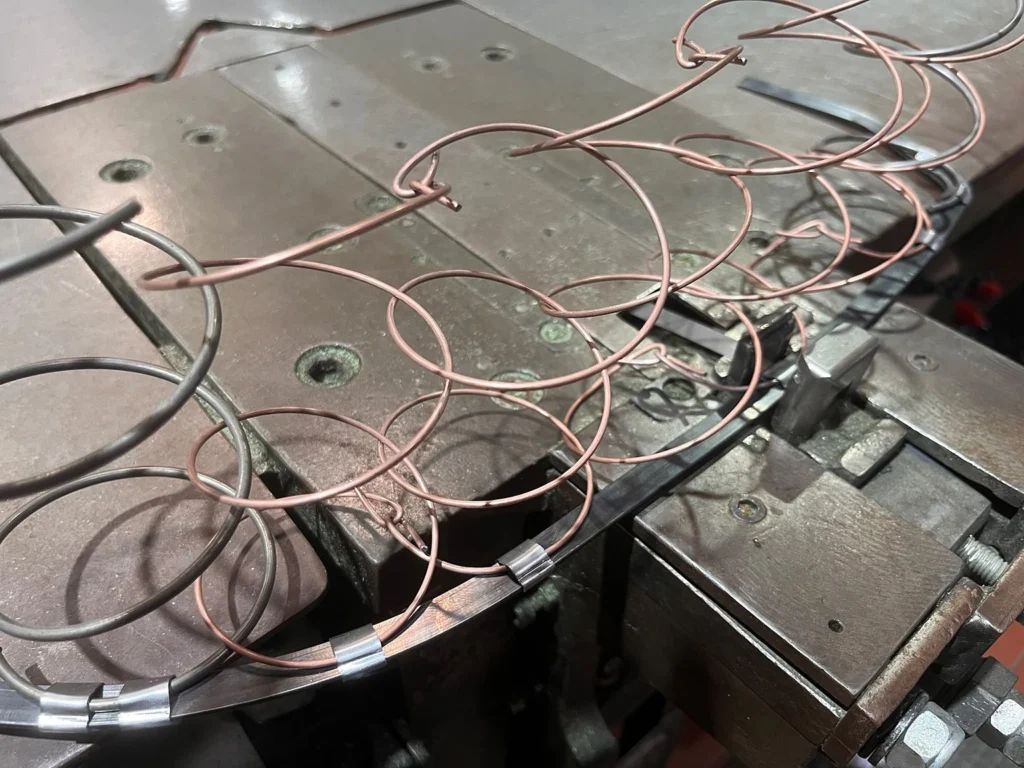 Randfedern werden an der WAFIOS-Klammermaschine mit Klammern aus Spaltband an der Randeinfassung befestigt